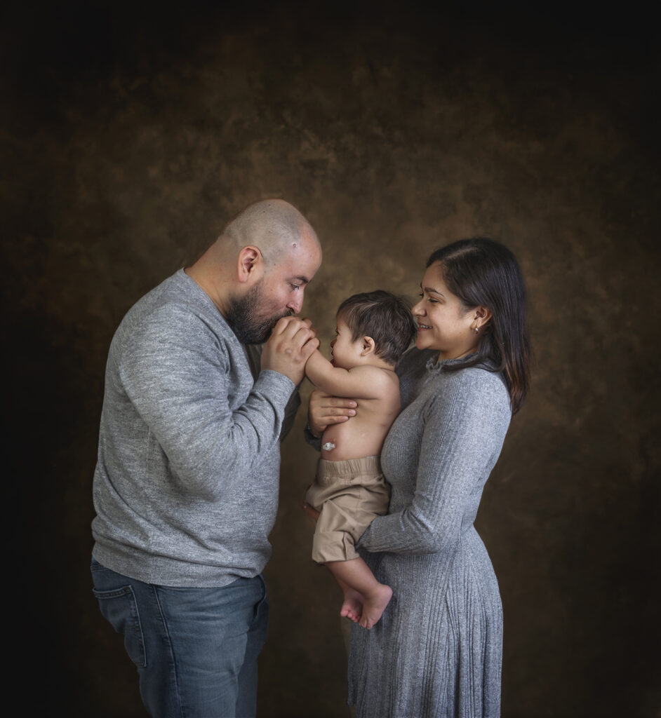 Mother and Father kissing their babies hand. How do I choose a good family photographer? 
